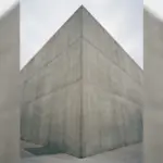 A monolithic concrete corner stands under an overcast sky