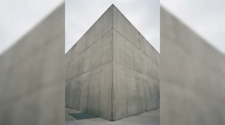 A monolithic concrete corner stands under an overcast sky